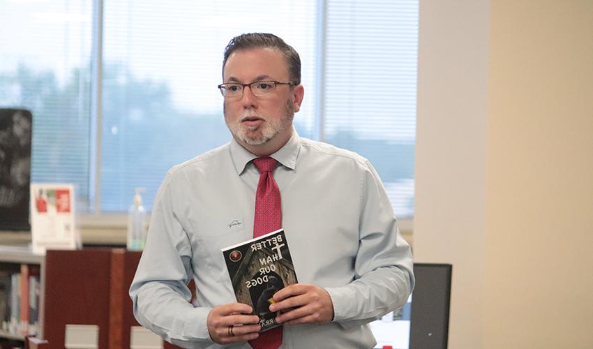 约翰J. Murray holding his book, "Better than our dogs"